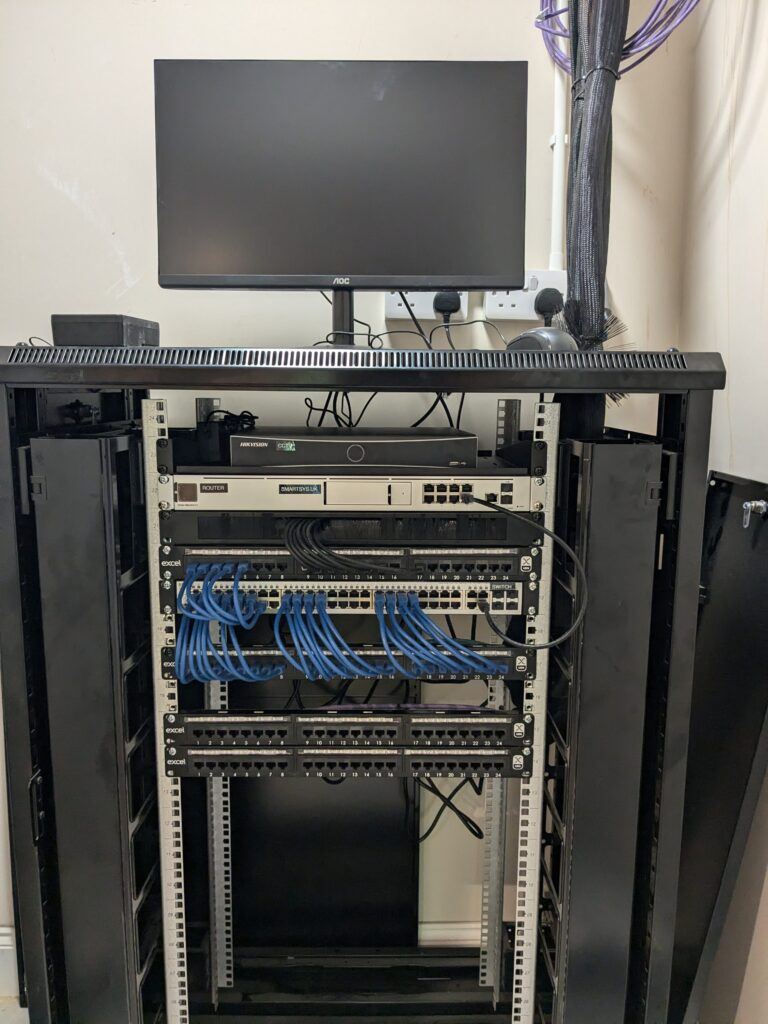 Labelled comms cabinet with UniFi router, switches and patch panels at Goldsborough Manor care home, York