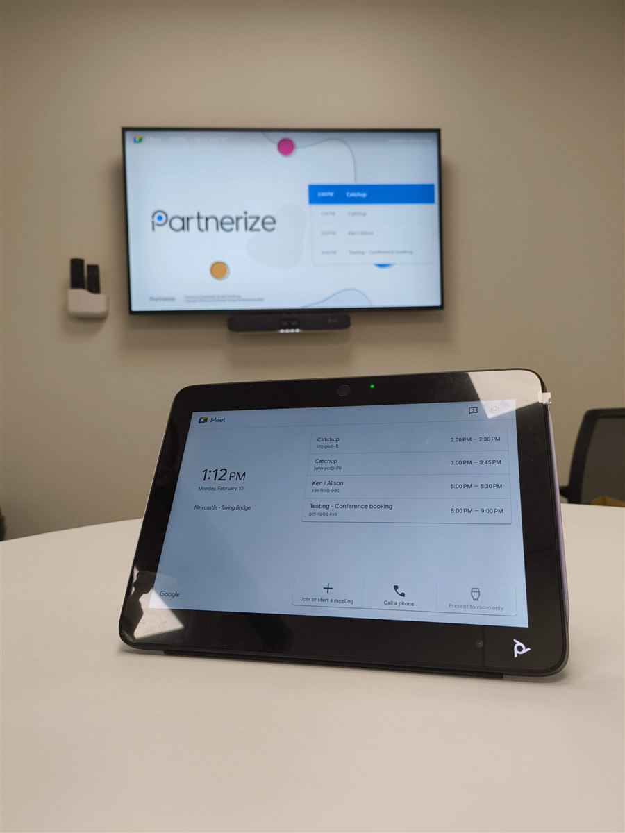 Poly video conferencing touch controller and wall-mounted screen in a Partnerize meeting room