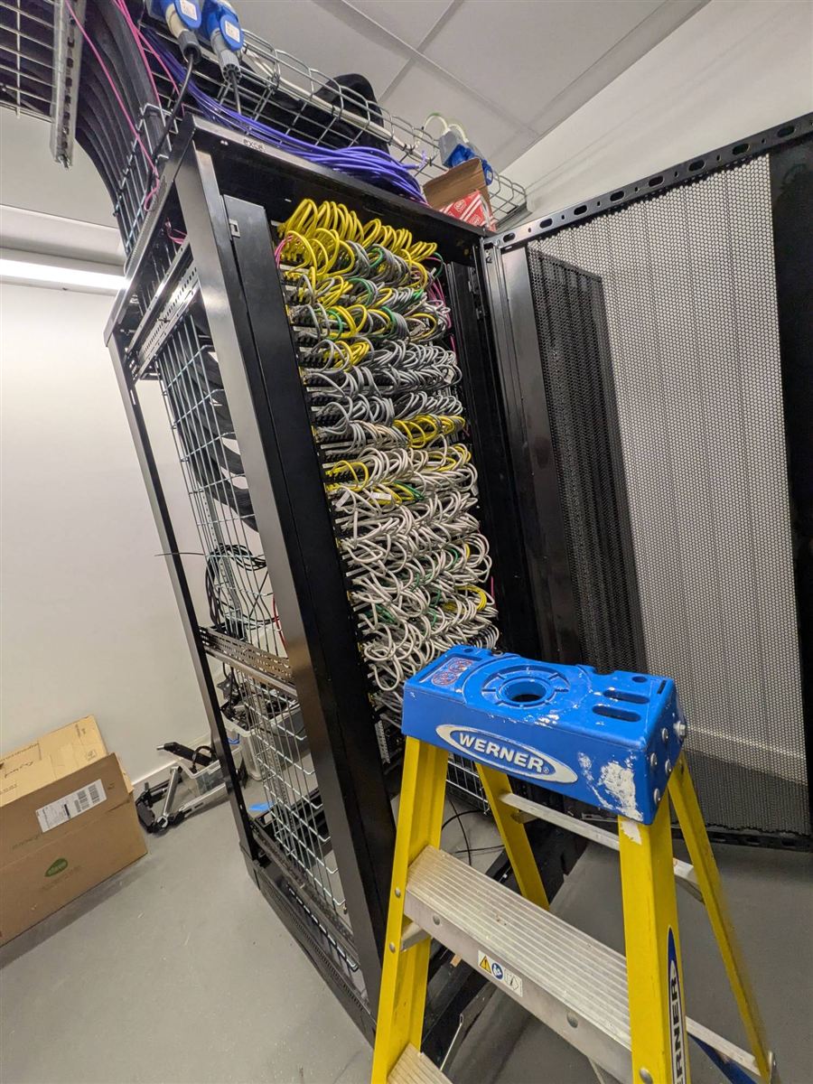 Floor-standing network cabinet with fully patched panels in a comms room