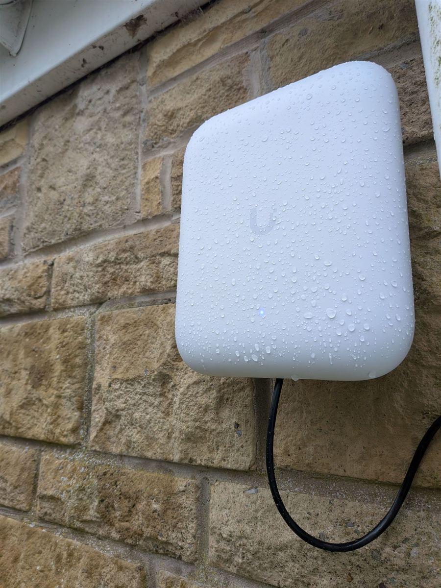 Outdoor UniFi Wi-Fi access point mounted on a stone wall