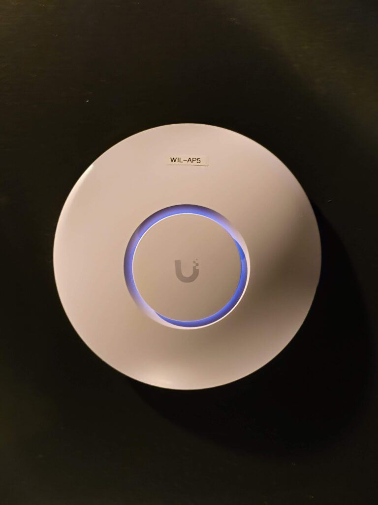 Close-up of a labelled UniFi Wi-Fi access point on a ceiling