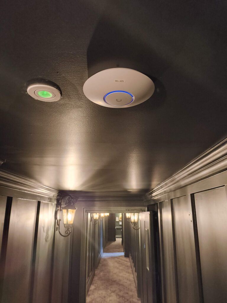 UniFi Wi-Fi access point on a hotel corridor ceiling