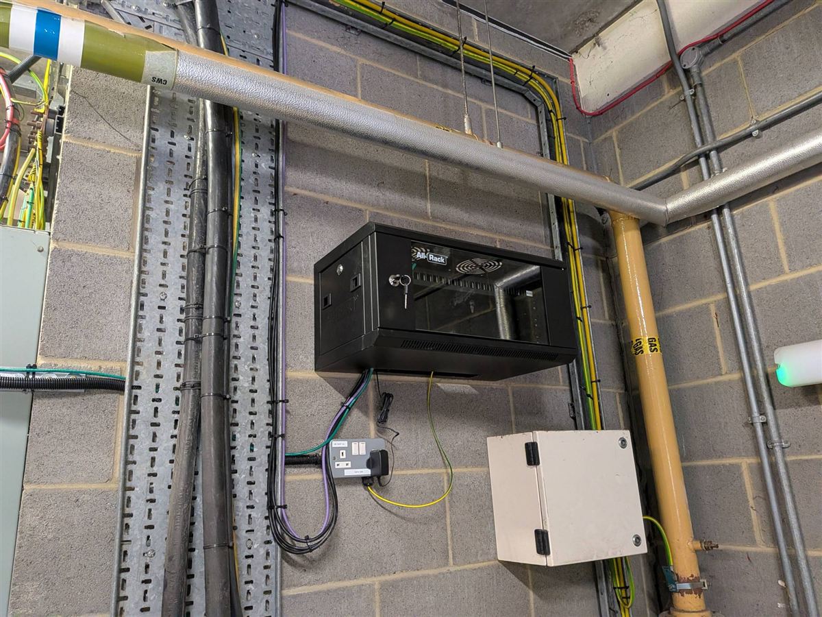 Wall-mounted network cabinet with neatly clipped cabling in a plant room